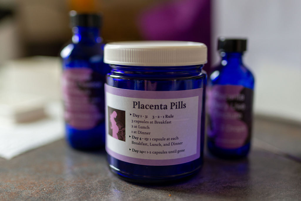 placenta pills jar purple with tincture bottles behind it, love in motion llc logo on sticker's jar