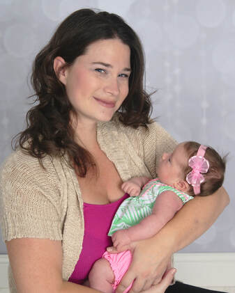 mom smiling and newborn baby pink outfits gray background